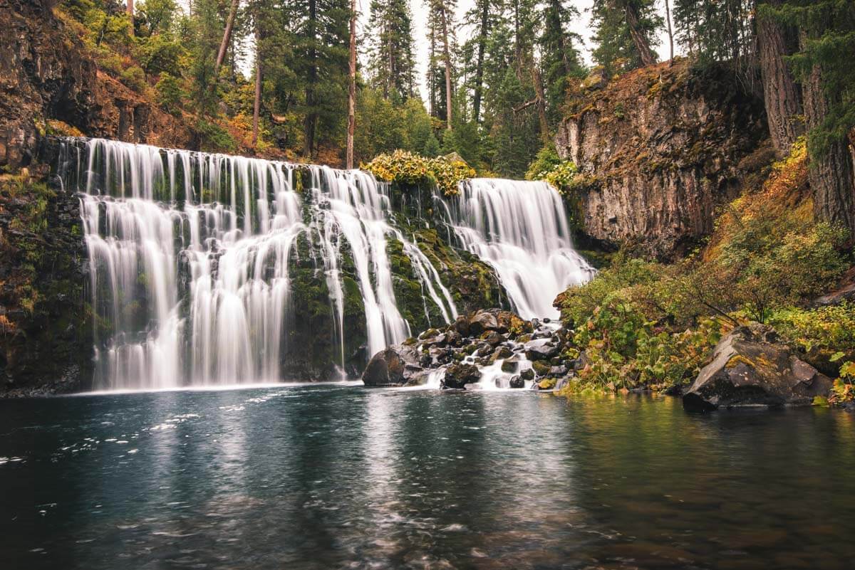 A long exposure of the wide Middle McCloud Falls in thr middle of a forest.