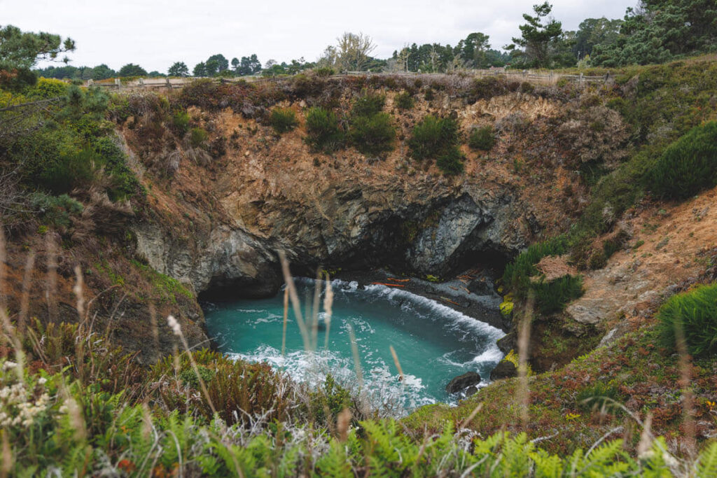 Blue ocean waves inside a sinkhole in Russian Gulch State Park in California.