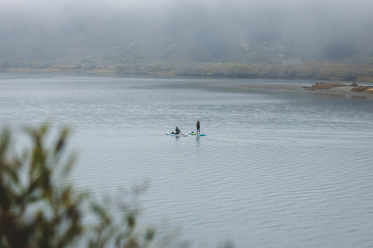 Two kayakers on a lake in Sonoma Coast State Park on a very foggy day.