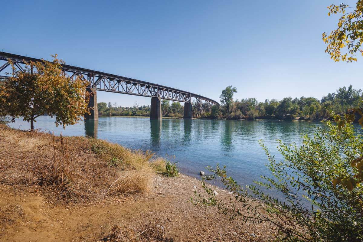A view of Lake Redding Park Bridge from the shoreline of a river.