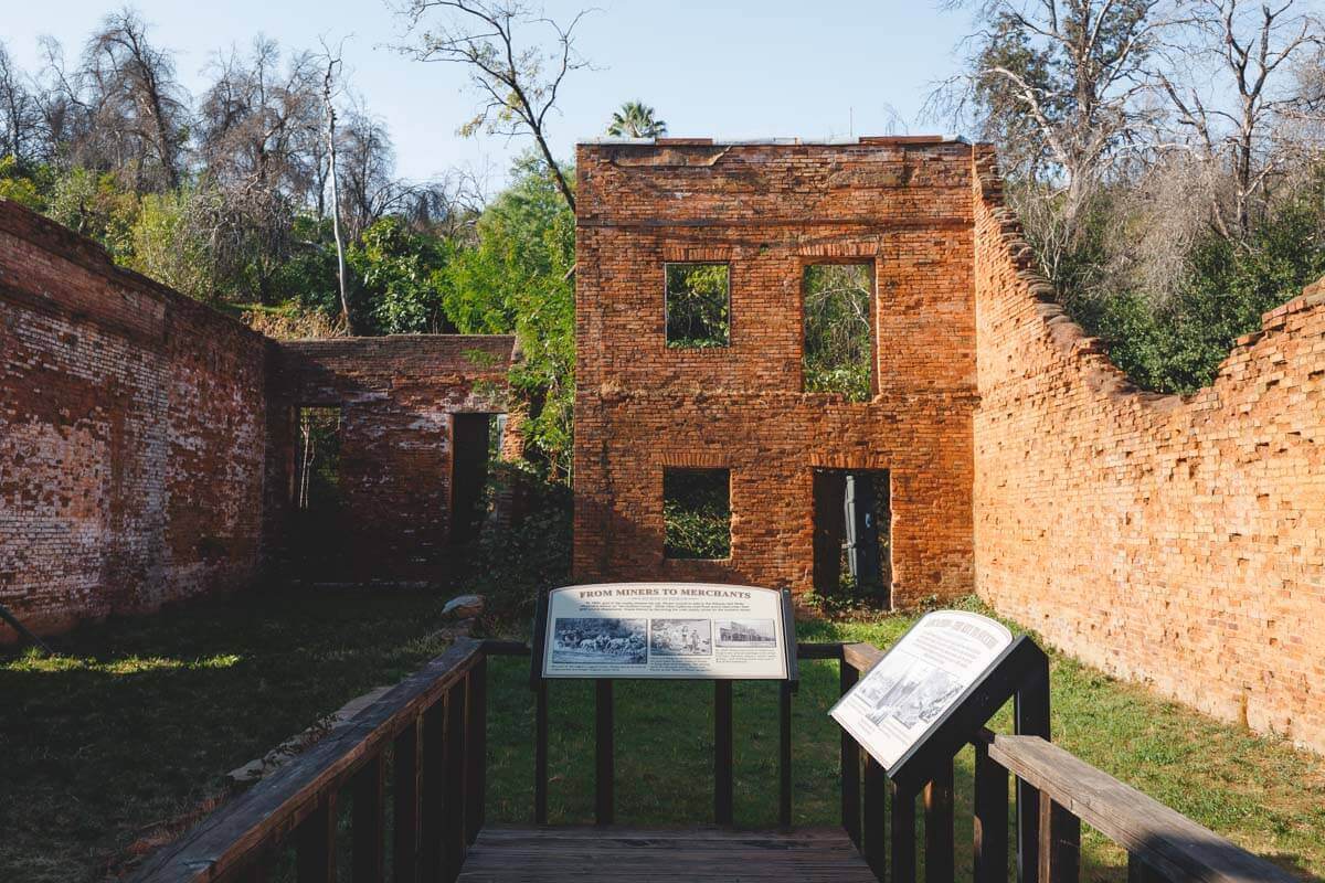 Ruins of an old brick house with informations signs in Shasta State Historic Park.