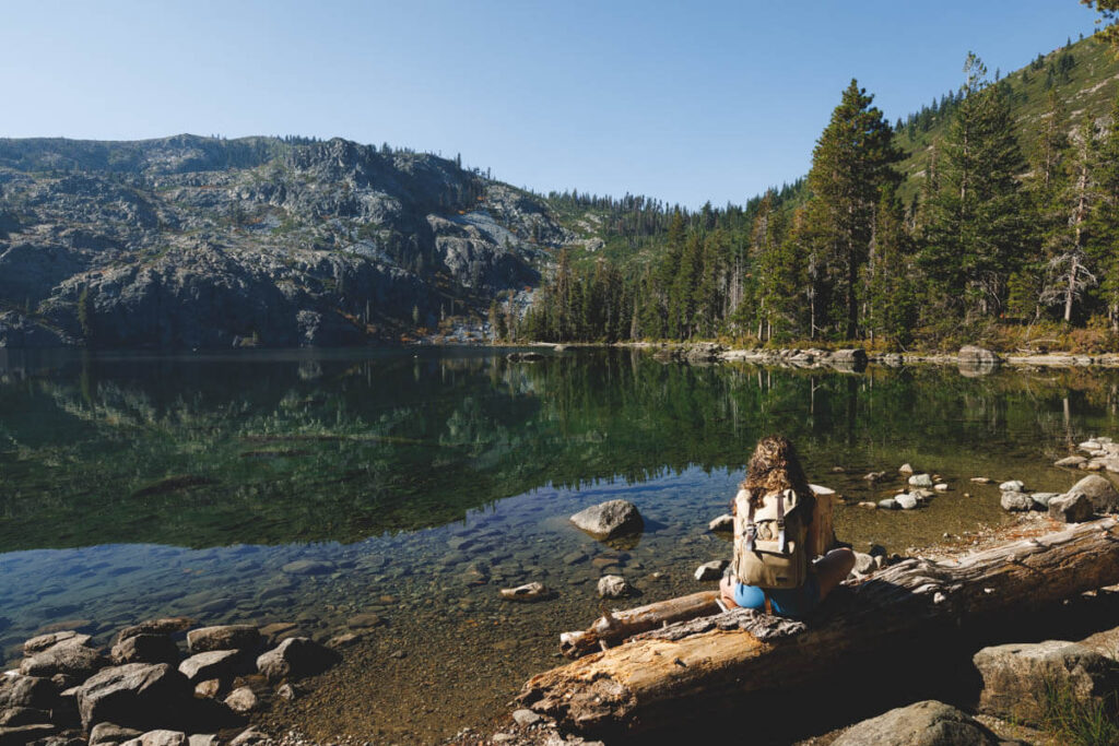 A woman sitting on a log next to Castle Lake.