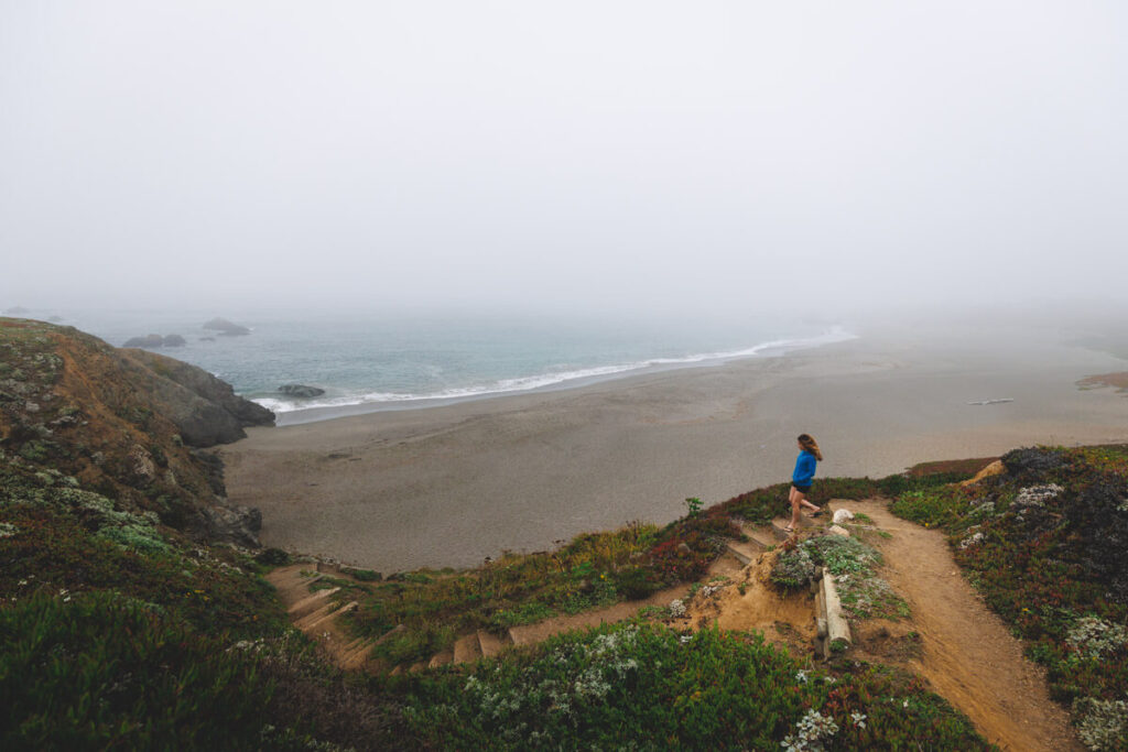 A woman walking down the stairs to Portuguese Beach in Sonoma Coast State Park.