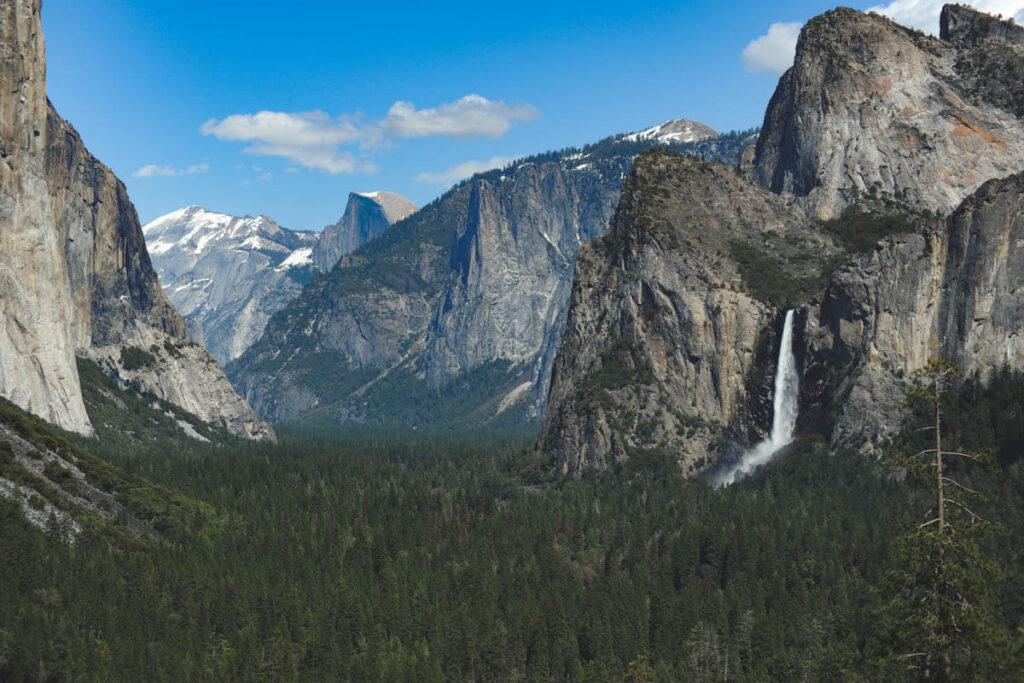 Distant falling cascade of Bridalveil Falls surrounded by famous mountains in Yosemite National Park.