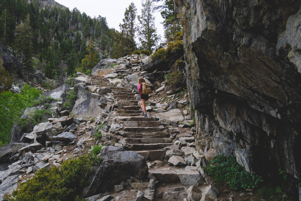 A lone hiker climbing stone stairs leading up to Eagle Falls in Northern California.