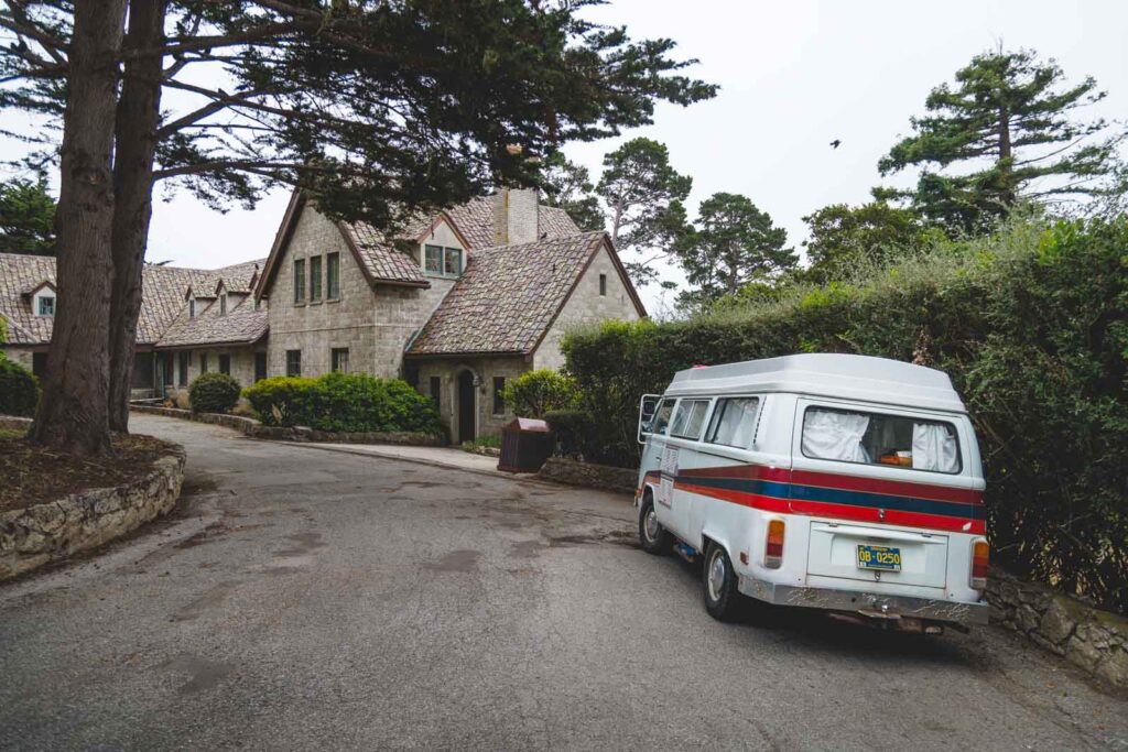 A VW camper parked next to the Carmel Mission building.