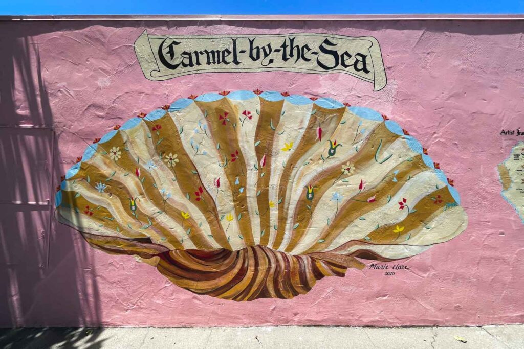 The Carmel-by-the-Sea seashell mural painted on a pink wall.