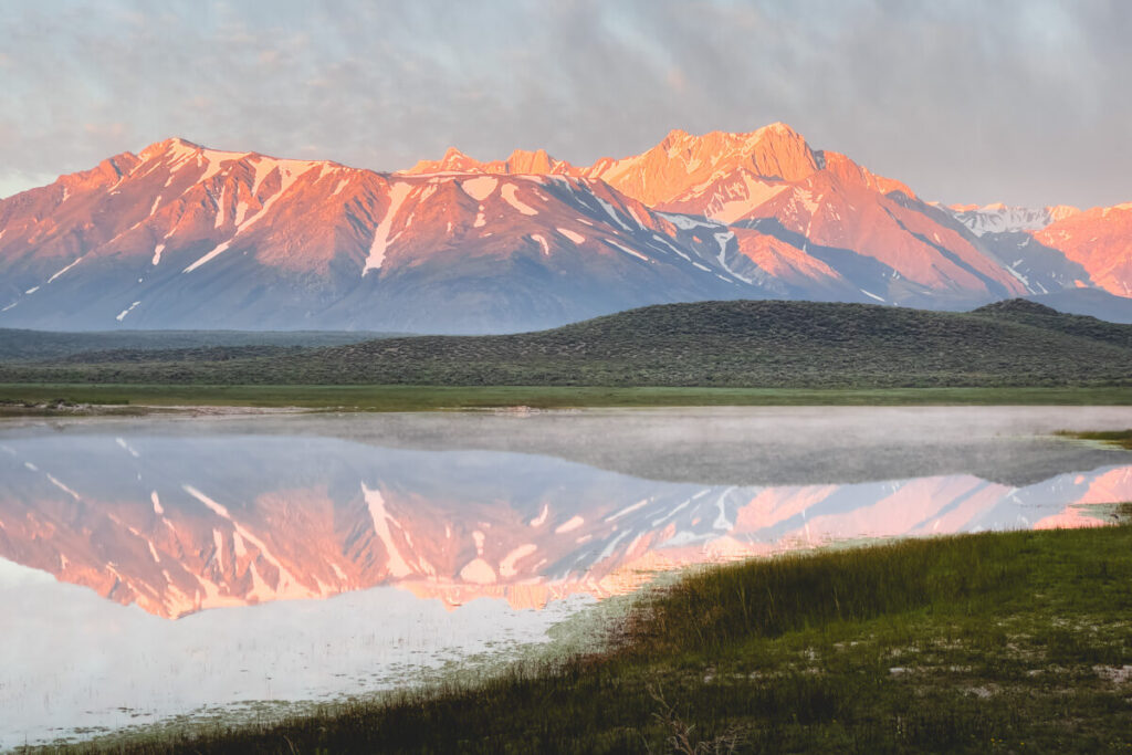 The Eastern Sierra Nevada mountains being relected on a still lake at sunrise.