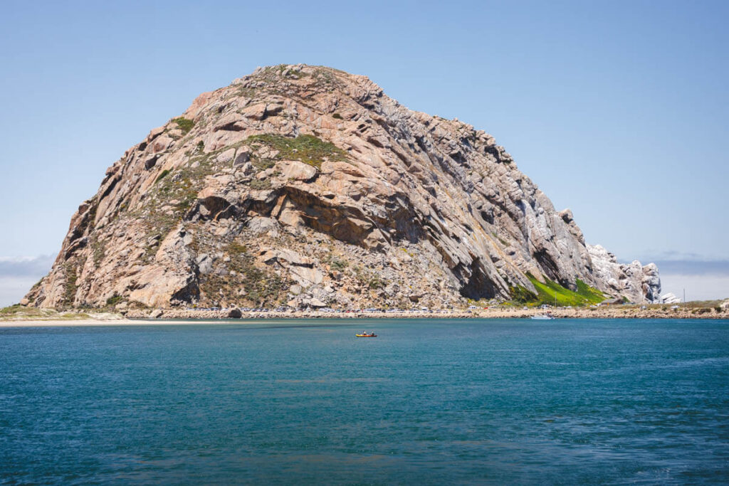 A kayak paddling in front of Morro Rock in Morro Bay State Park in California.