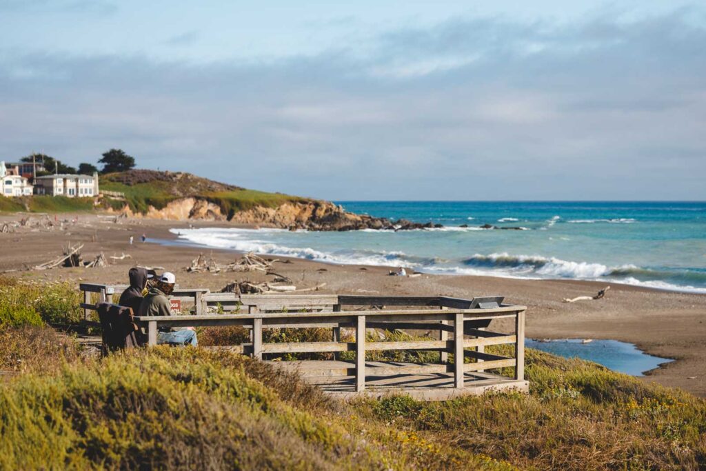 Two people sitting on a bench overlooking Moonstone Beach in San Simeon State Park.