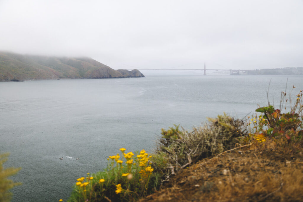A view looking out over and overcast and gray San Francisco Bay and the Golden Gate Bridge.