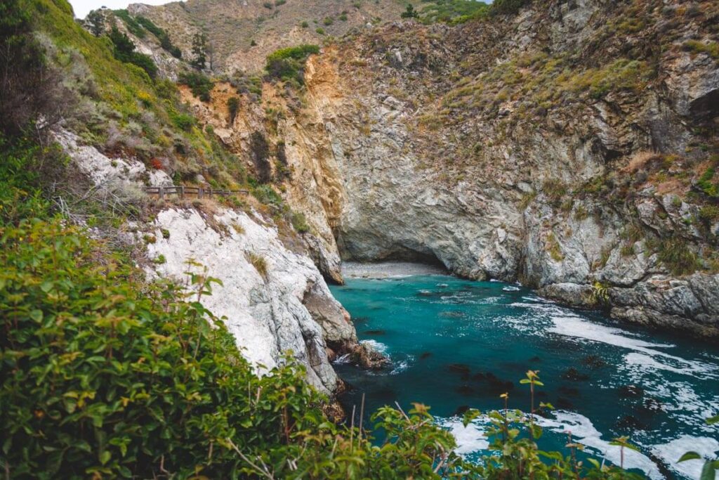 The blue ocean water of Partington Cove surrounded by cliffs.