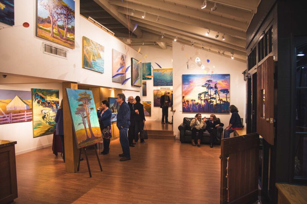 A group of people admiring art hanging in the Carmel-by-the-Sea art gallery.