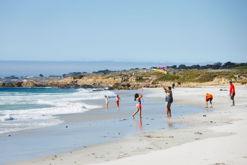 Families playing on an empty sand beach along the 17 Mile Drive.