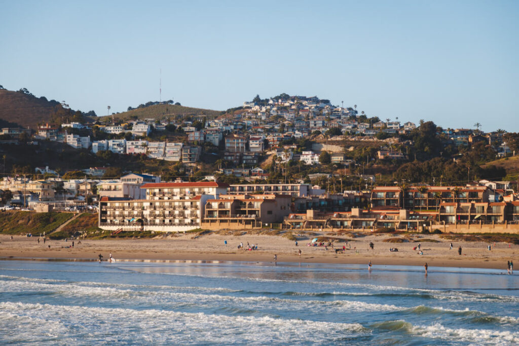 Hotels, apartments and houses built on a hill glowing in the sunset light at Pismo State Beach.