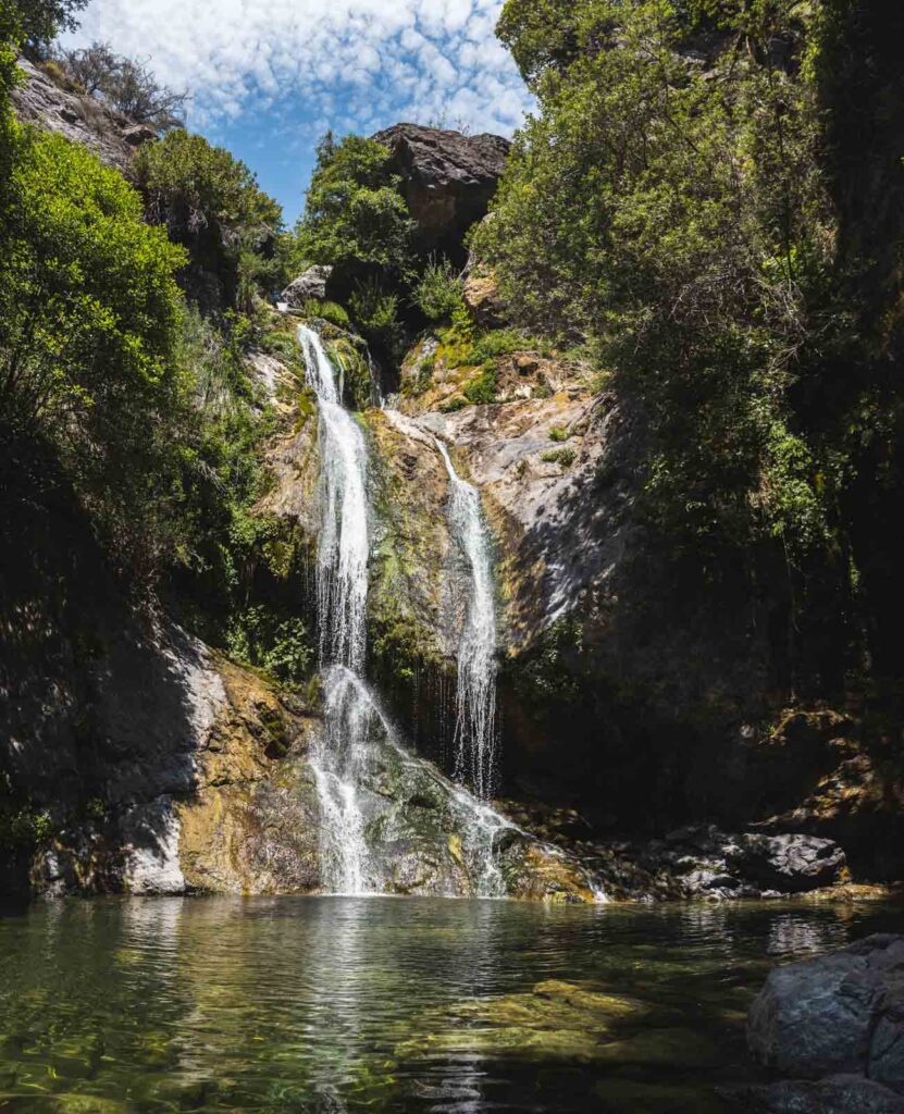 The dual cascade of Salmon Creek Falls down the in the middle of a forest.