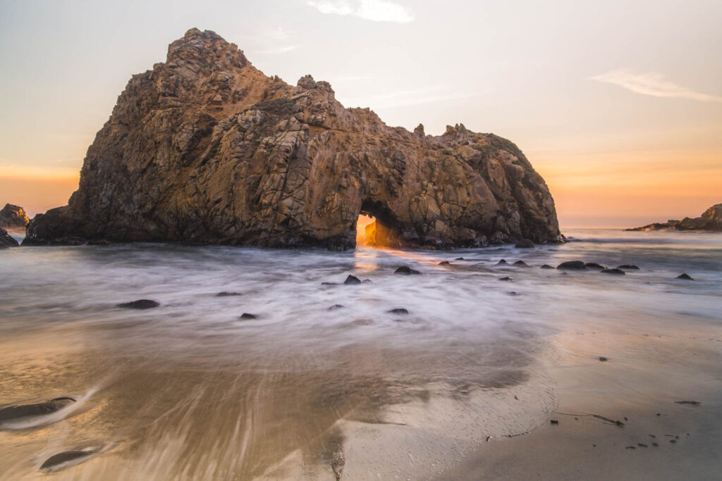 Sunset light shining through Keyhole Arch on Pfeiffer Beach along Big Sur.