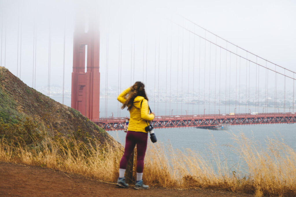 A tourist at the Battery Spencer viewpoint looking out over the Golden Gate bridge.