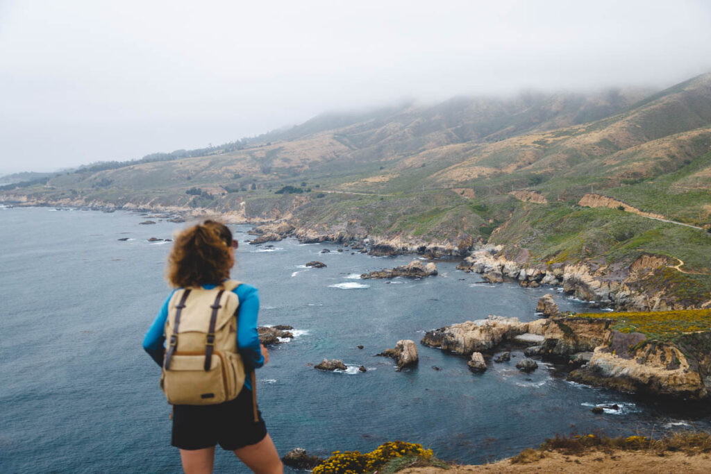 A female hiker looking out over a view of Soberanes Point in Garrapata State Park.