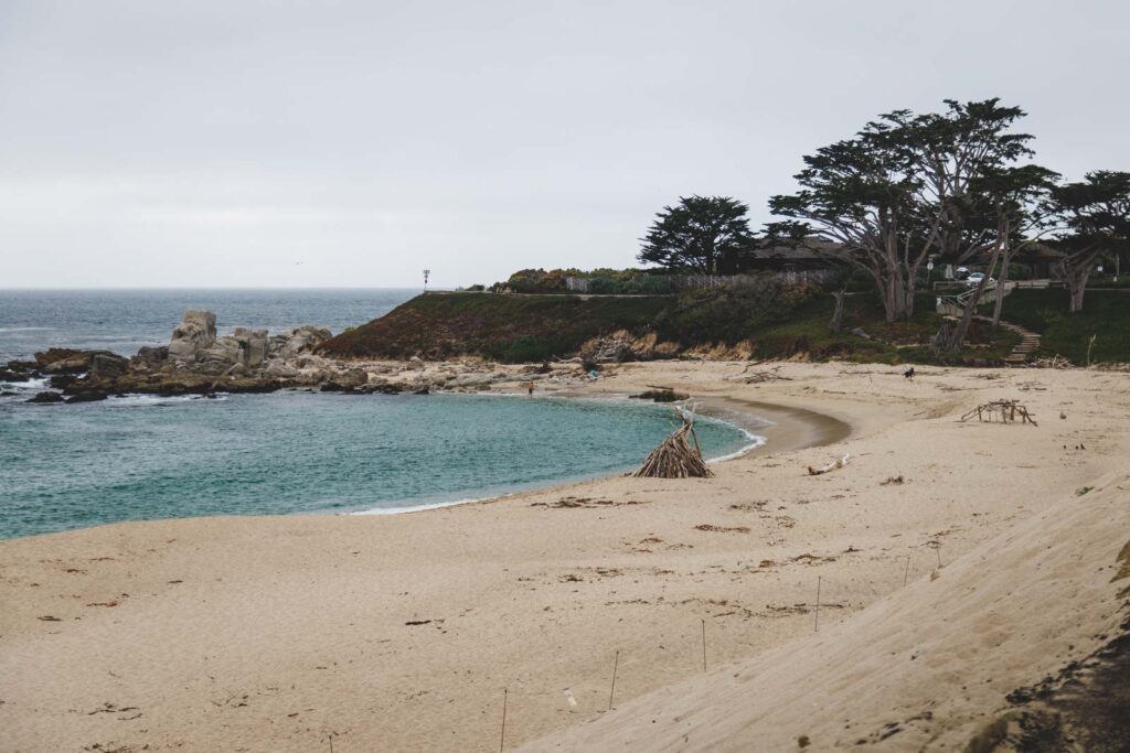 A wooden pyre someone has build on an empty Carmel River State Beach on an overcast day.