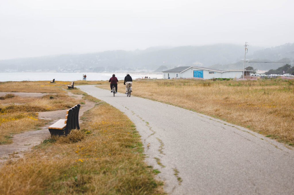 Cyclists along the Half Moon Bay coastal trail on an overcast day.