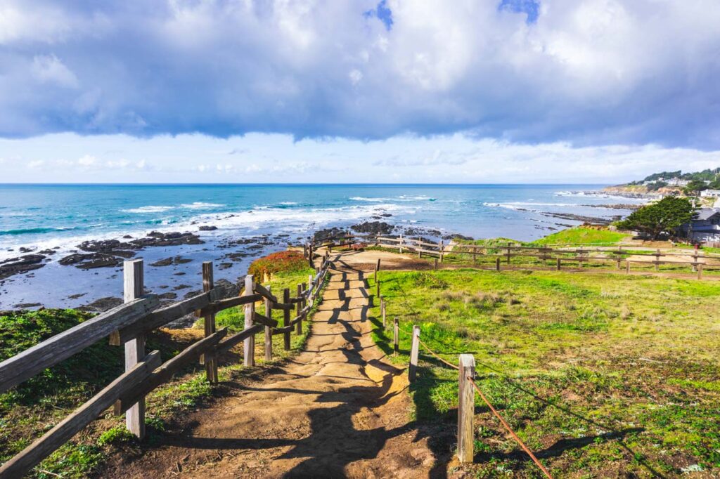 A fenced path following the cliff edge towards Moss Beach in the Fitzgerald Marine Reserve.