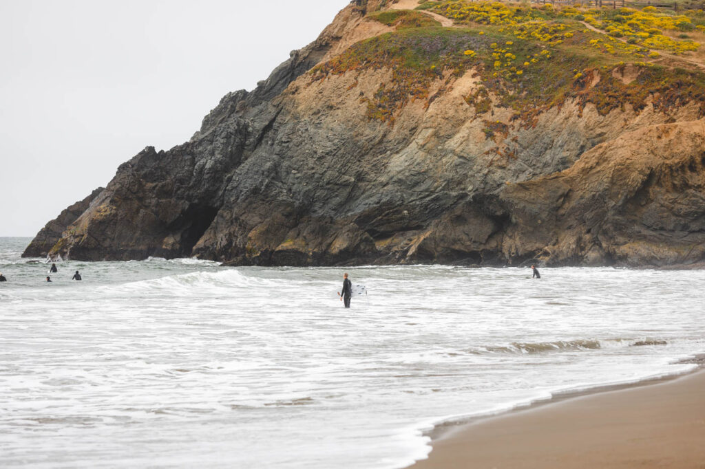 Surfer standing in the wash of the ocean at Rodeo Beach in San Francisco.