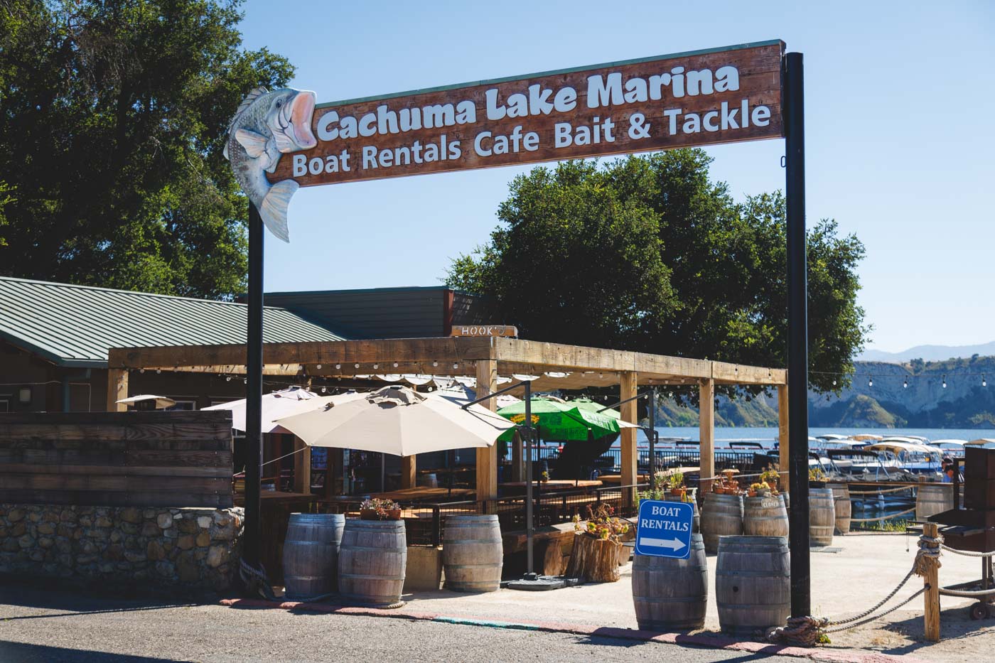 Entrance and sign for Cachuma Lake Marina boat rents in California with views over the pier and restaurant.