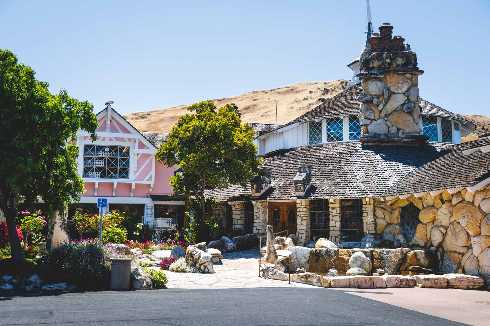 Unique looking Madonna Inn accommodation with stone walls and a hill behind it in San Luis Obispo.