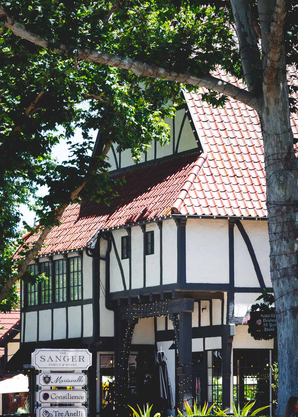 Danish-style building framed by a tree with a sign for Sanger Winery in Solvang.