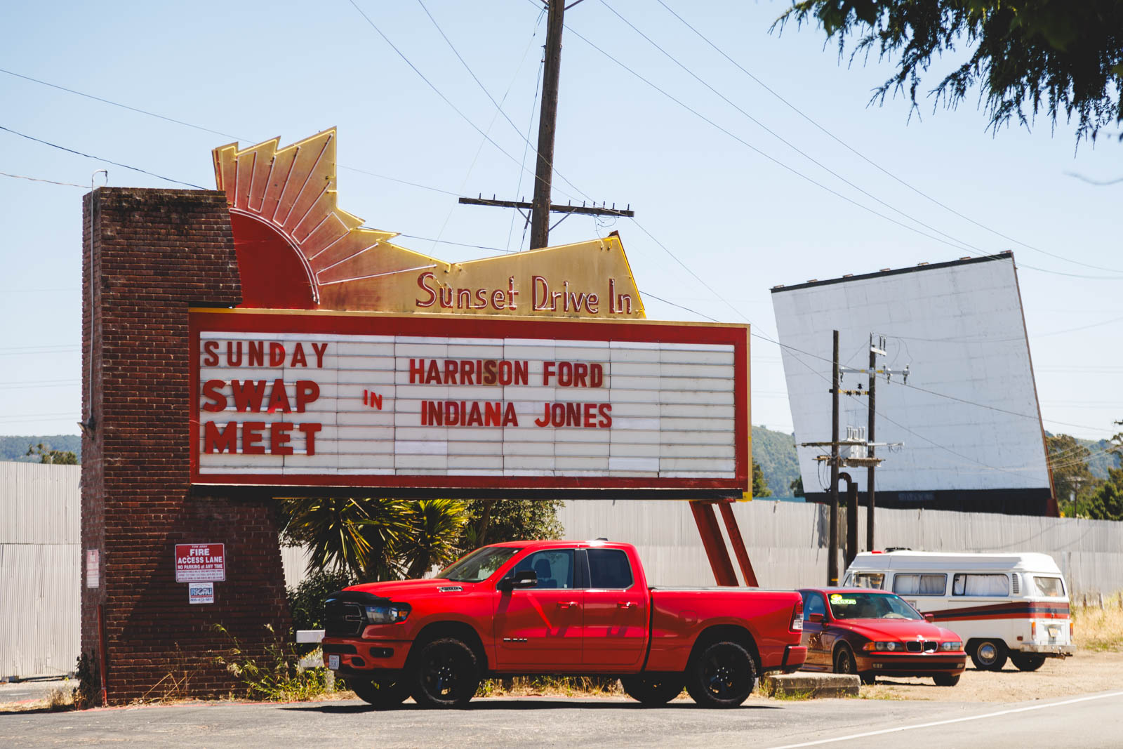 Red truck parked in front of the Sunset Drive-In sign which shows Indiana Jones playing in San Luis Obispo.