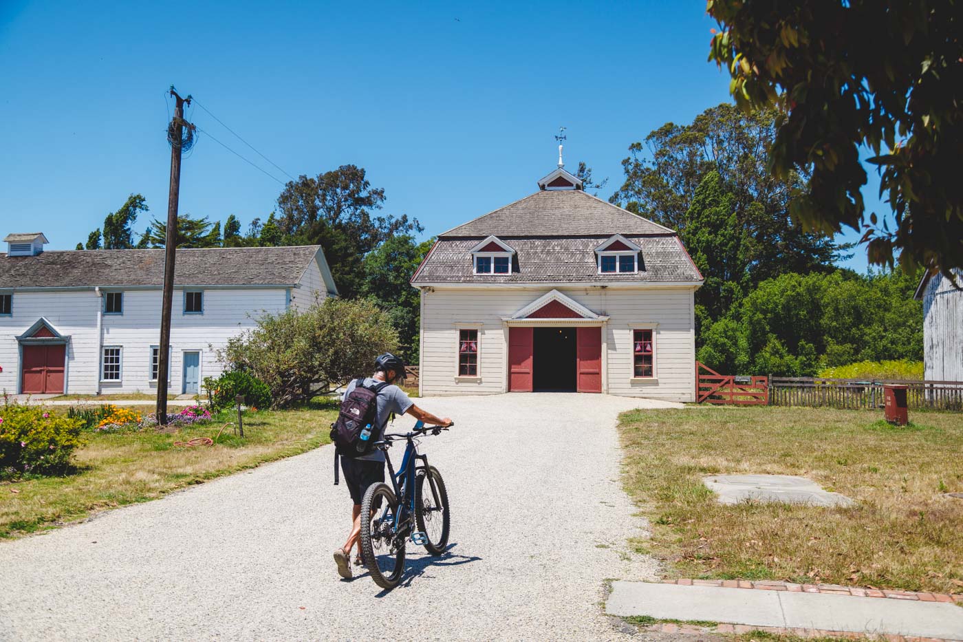 Cyclist pushing a bike along a path towards a restored building in Wilder Ranch State Park.