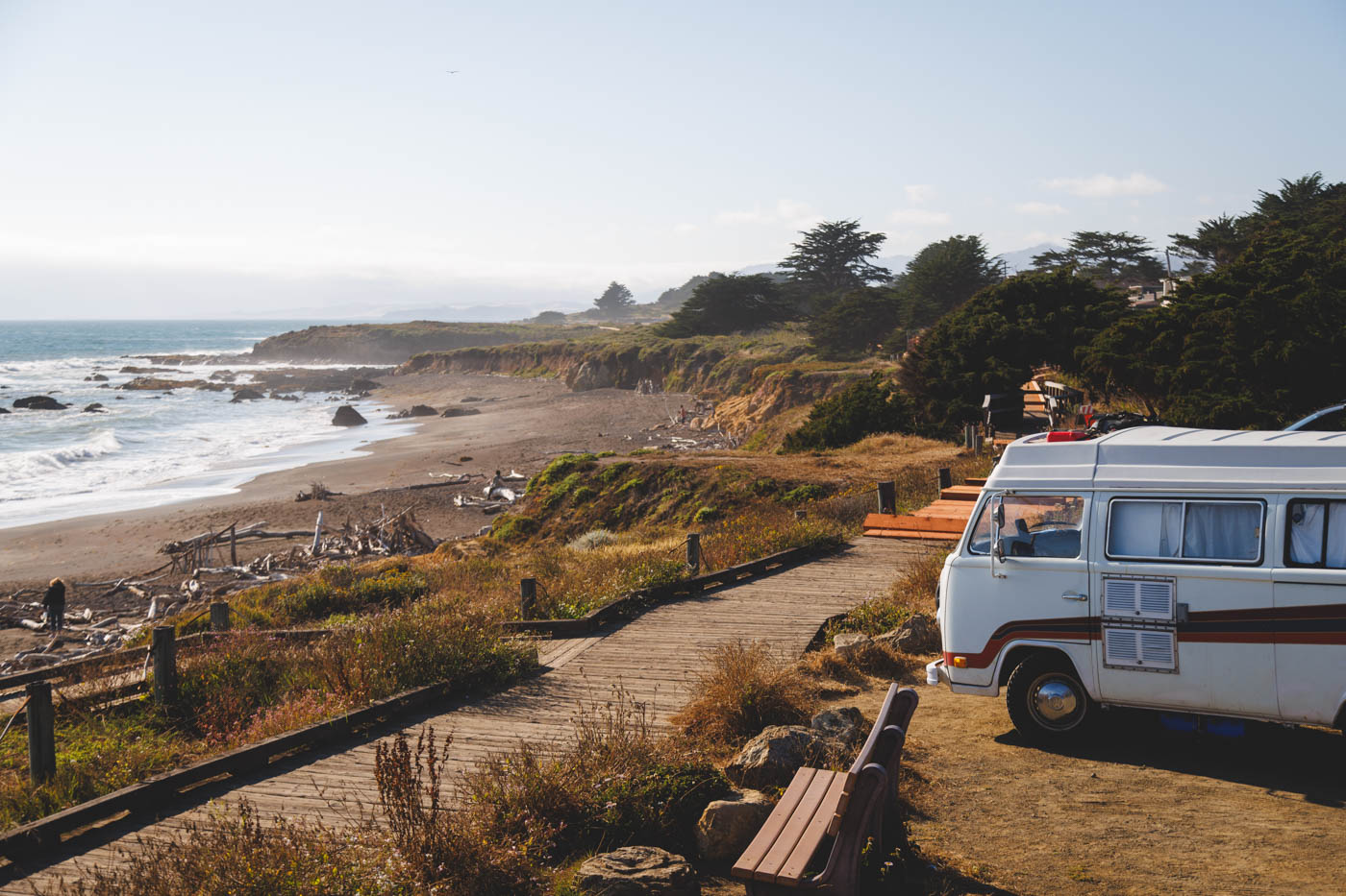 A white RV parked up along the Moonstone Scenic Driver overlooking a beach at golden hour.