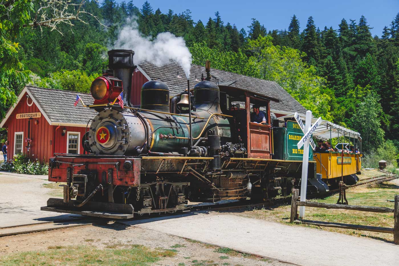 A steam train locomotive driving through the Roaring Camp Train Depot.