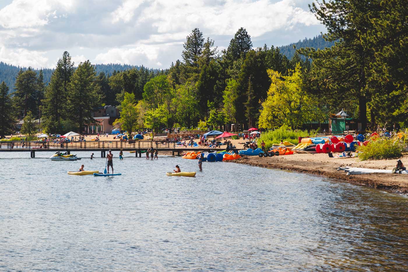 Kayaker, paddle boarders and tourists enjoying a sunny day on Kings Beach beside Lake Tahoe.