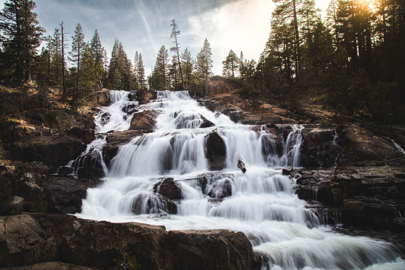 A long exposure of the Lower Glen Alpine Falls at sunset with trees around.