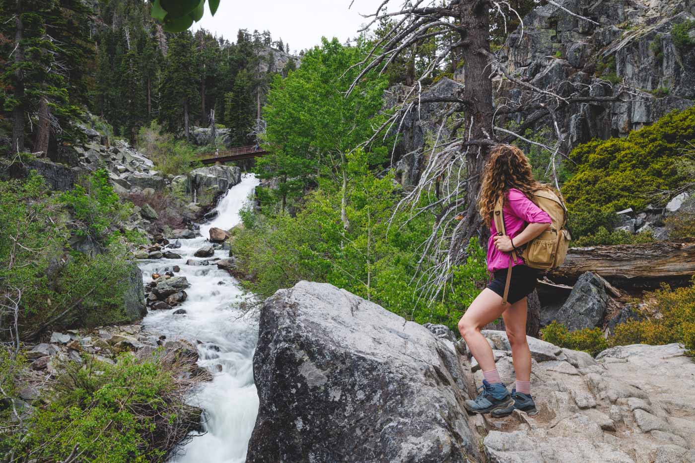 Nina in hiking gear standing beside Eagle Falls surrounded by rocks and trees.