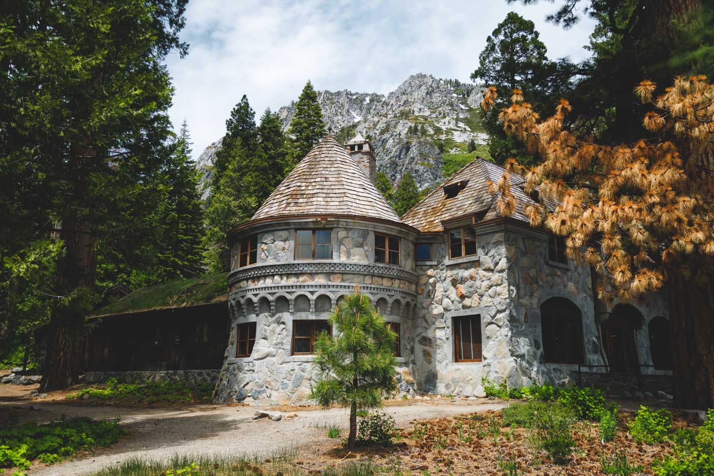 The stone Vikingsholm mansion build in the middle of the forest with a backdrop of mountains.
