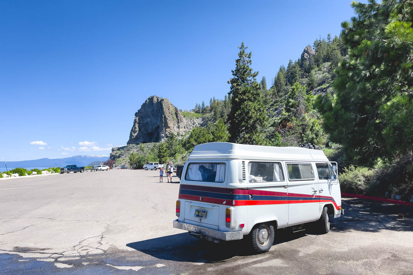 White campervan parked in a public car park with a view of Cave Rock beside Lake Tahoe.