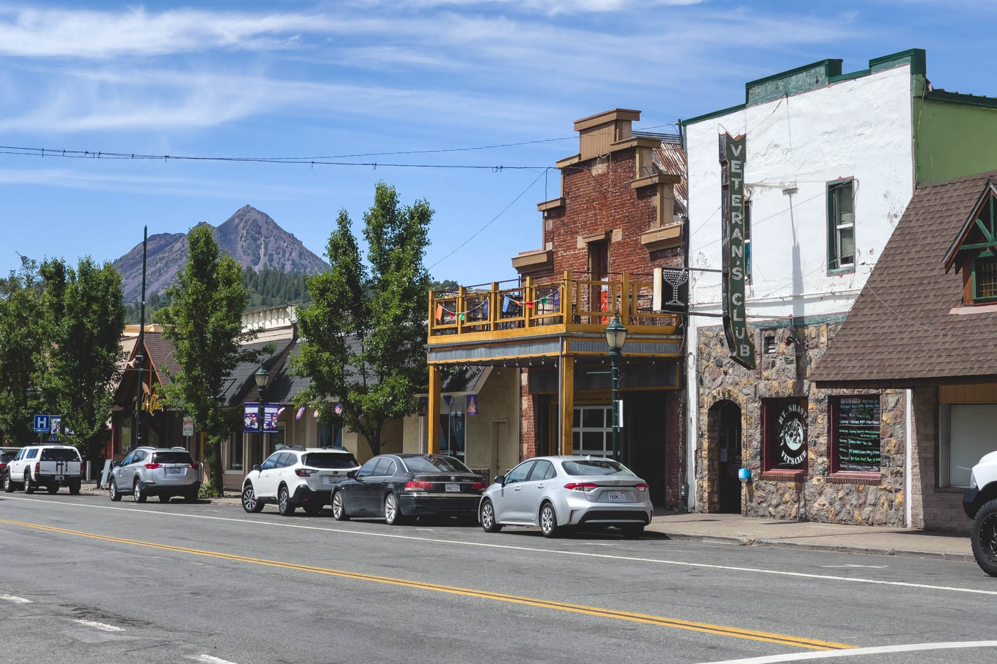 A main road of Mount Shasta with a couple of historic looking buildings and a mountain in the distance.