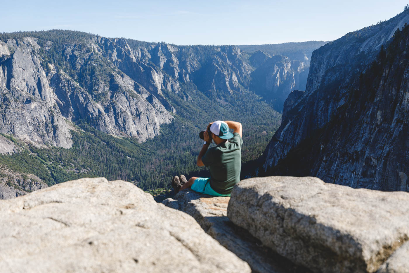 Garrett sitting at the top of the Upper Yosemite trail taking photos of the views over the national park.