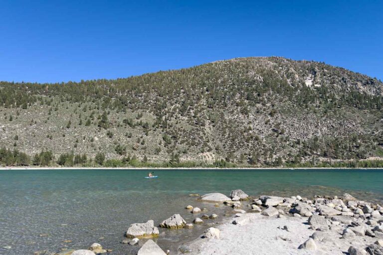 Kayker out on June Lake on a sunny day with some hills in the back.